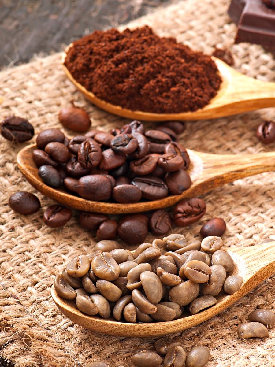 Green and brown coffee beans in bowls